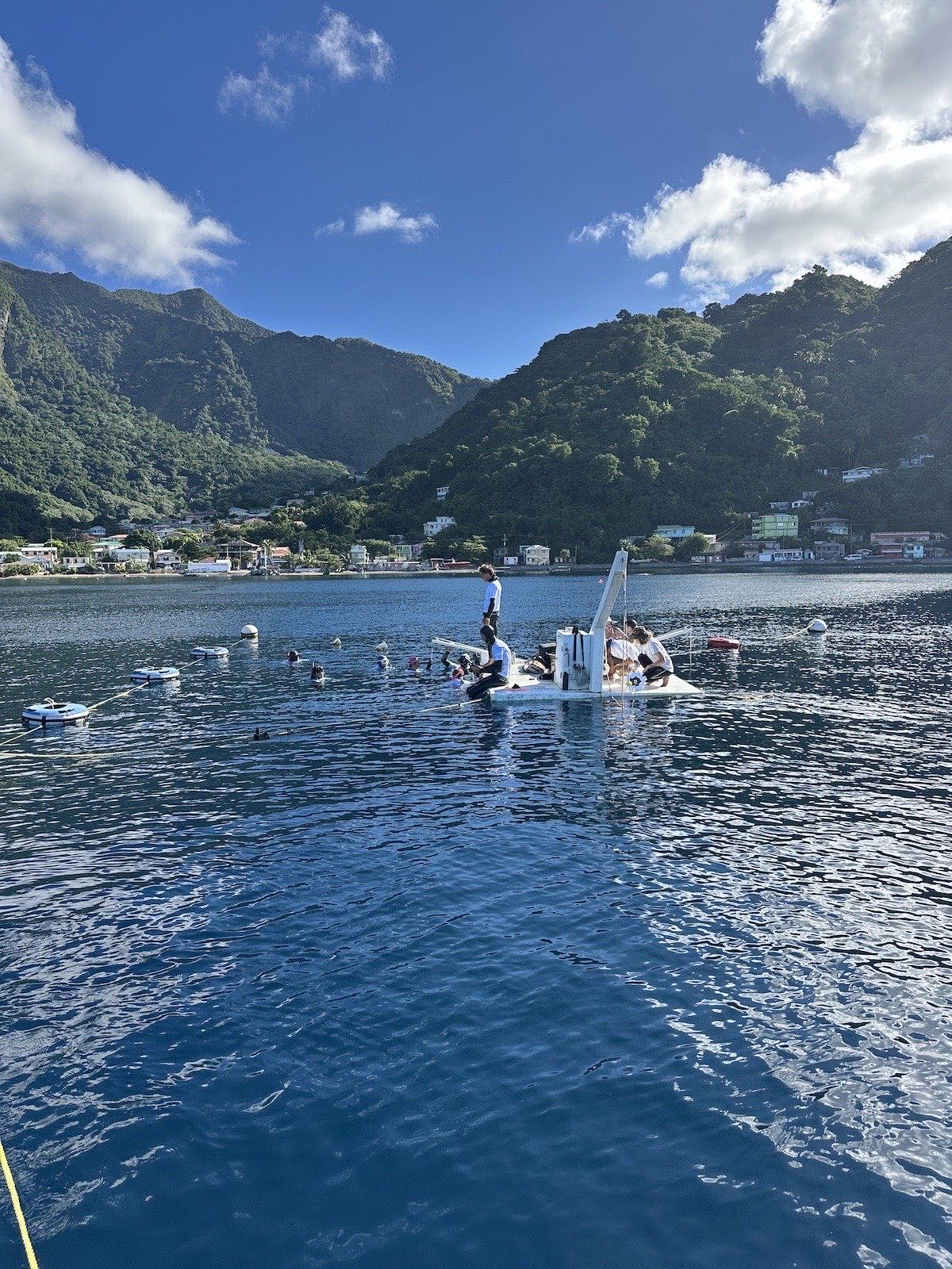 The dive platform on a flat-calm Soufrière Bay, the village behind it