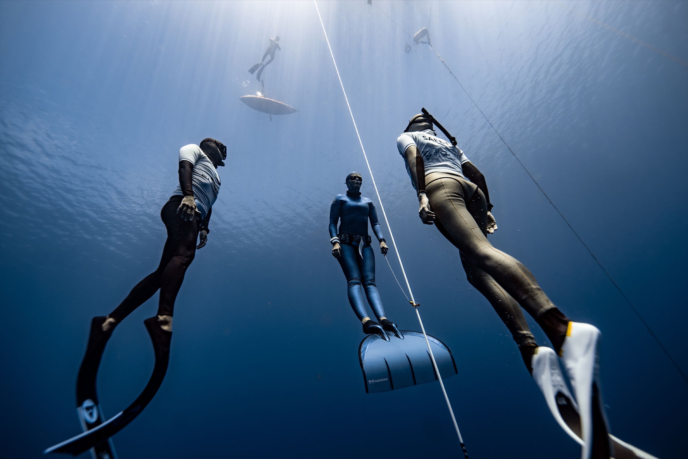 Freedivers descending the competition line flanked by safety in Soufrière Bay, Dominica