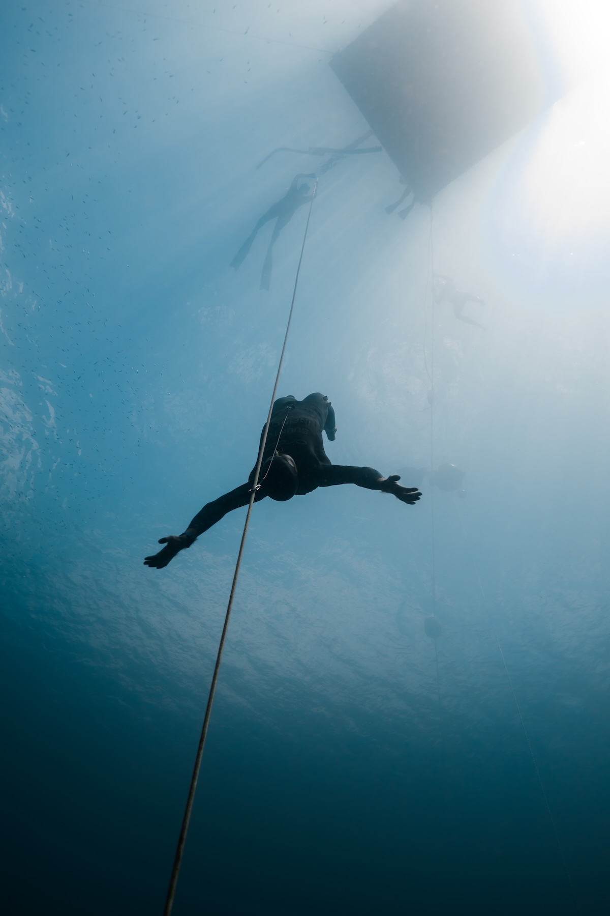 No-fins diver ascending with arms spread beneath the platform