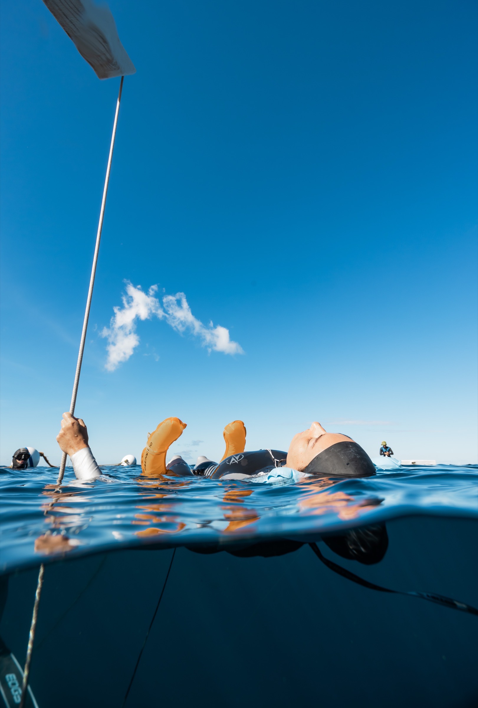A freediver recovering at the surface with safety alongside