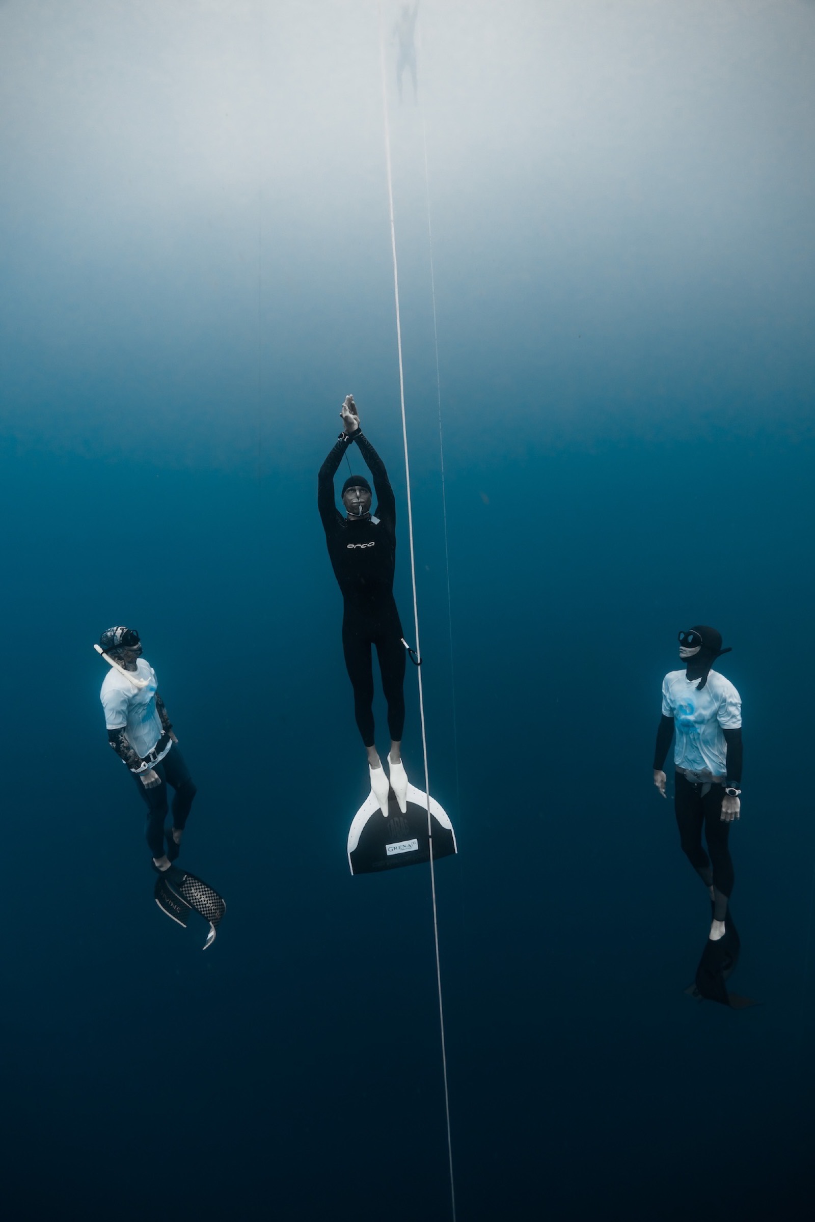 Matt Malina ascending on the monofin, a safety diver on each side