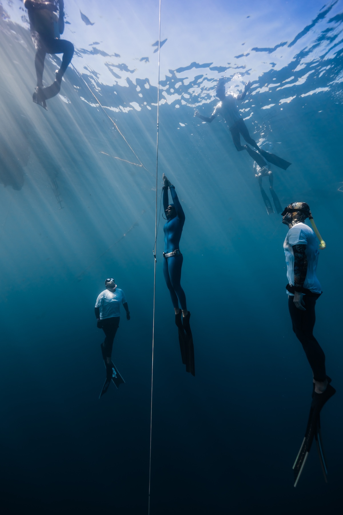 An athlete descending the line flanked by safety divers at Blue Element