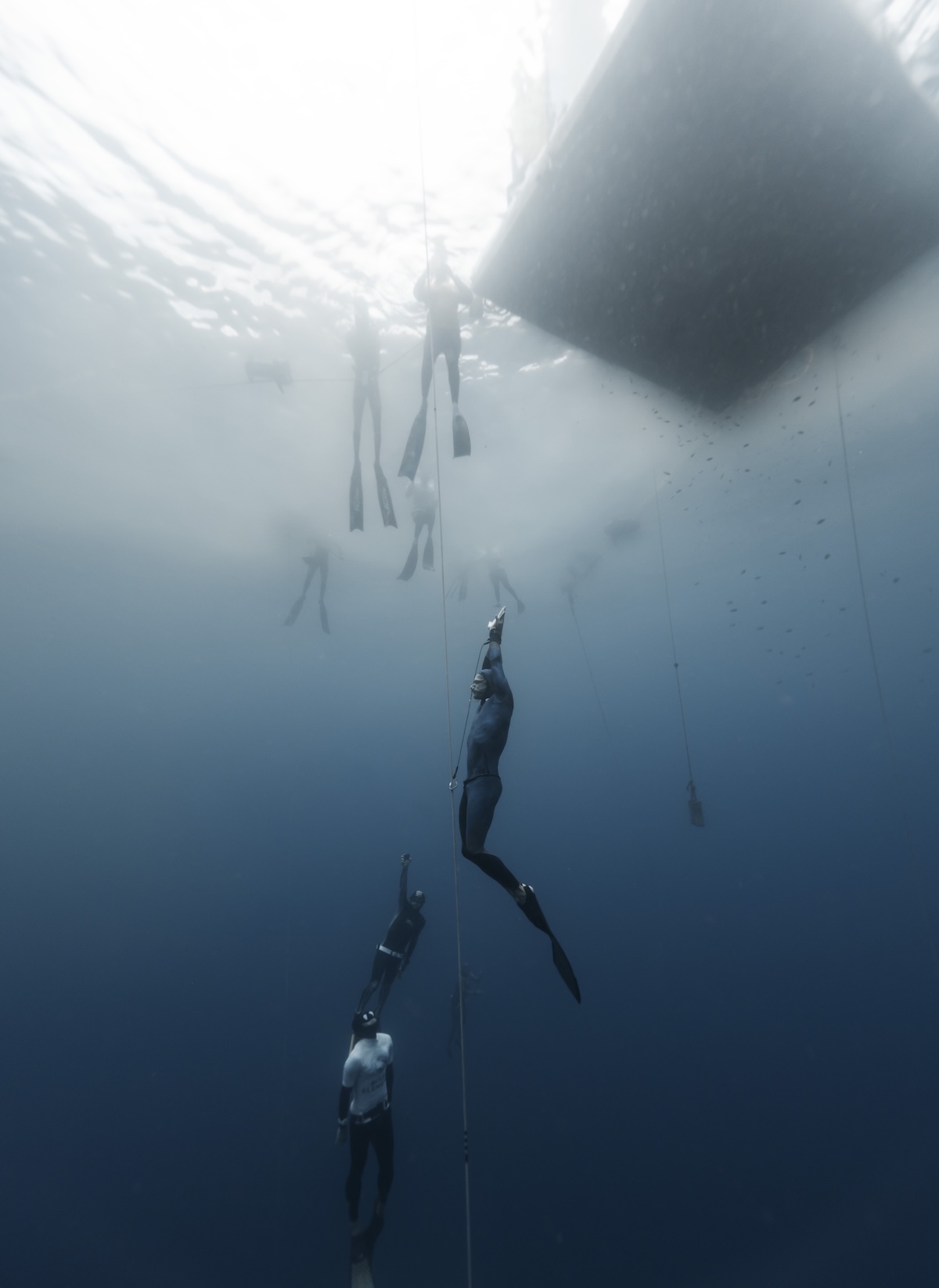 Safety divers meeting an ascending freediver at depth