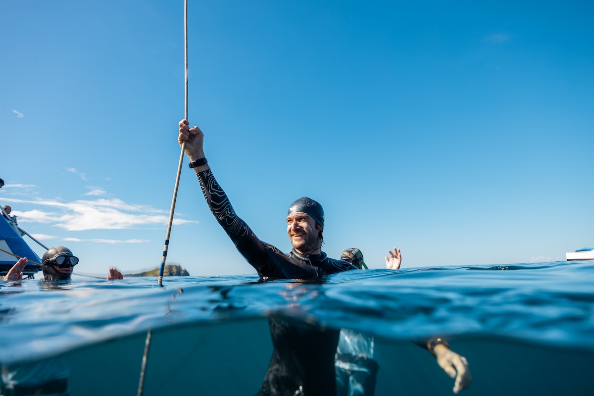A freediver surfaces smiling after a clean competition dive
